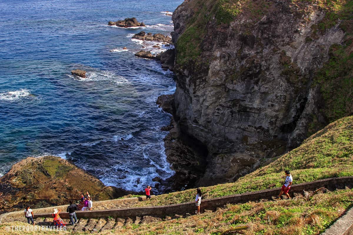 A stone staircase leads visitors to the base of the cliff.