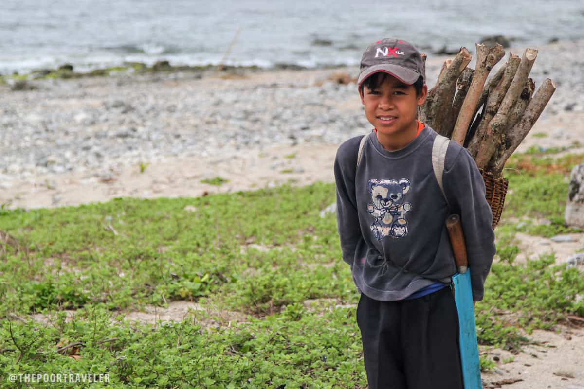 A boy collecting sticks by the shore